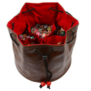 Brown leather dice bag with red interior filled with colorful dice on a white background