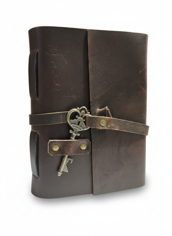 Brown leather journal with a strap and key on a white background